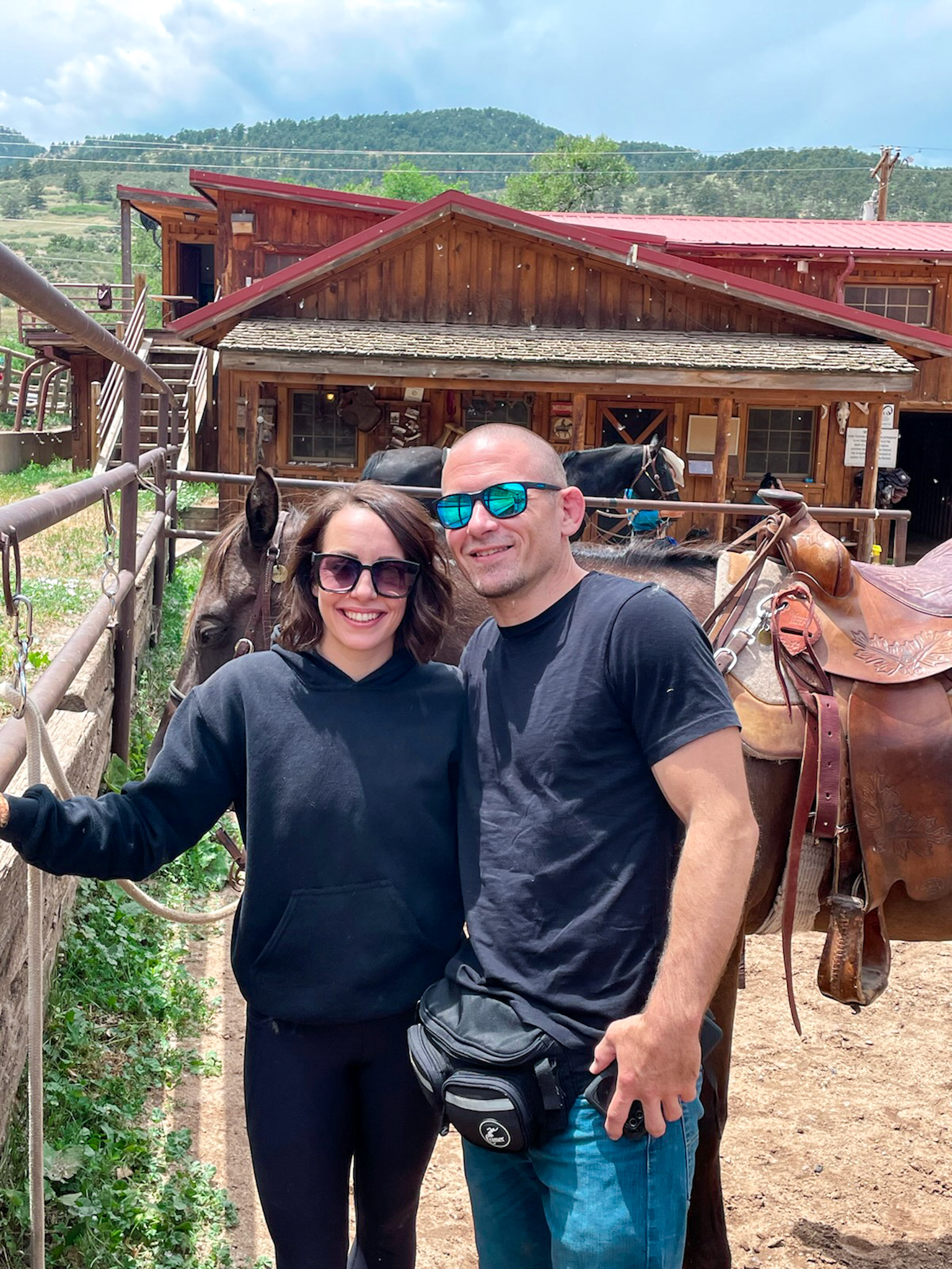 A man and woman smiling for a photo at a horse ranch before the trail ride