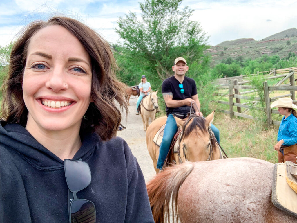 A selfie of a woman with a man on horseback in the background